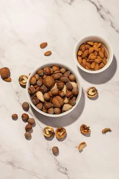 Different nuts in a white plate with a nutcracker on a gray table Stock Photos
