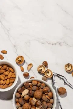 Different nuts in a white plate with a nutcracker on a gray table Stock Photos