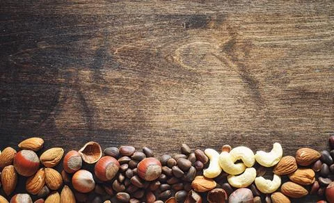 Different nuts on a wooden table. Cedar, cashew, hazelnut, walnuts and a sp.. Stock Photos