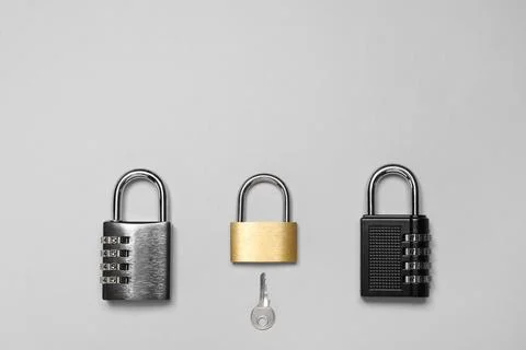 Different padlocks and key on grey background, flat lay. Space for text Stock Photos