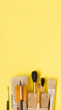 Different paint brushes on yellow background Stock Photos
