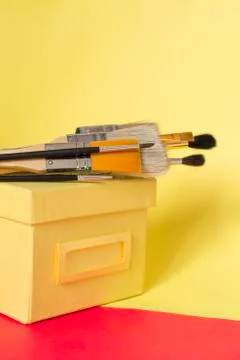 Different paint brushes on yellow background Stock Photos