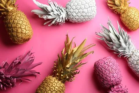 Different painted pineapples on pink background, above view. Creative concept Stock Photos