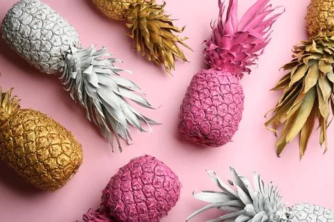 Different painted pineapples on pink background, above view. Creative concept Stock Photos