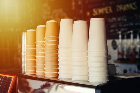 Different paper cups for coffee stacked in cafe interior Stock Photos