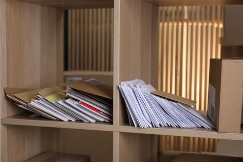 Different paper envelopes and parcel on wooden shelves in post office Photos