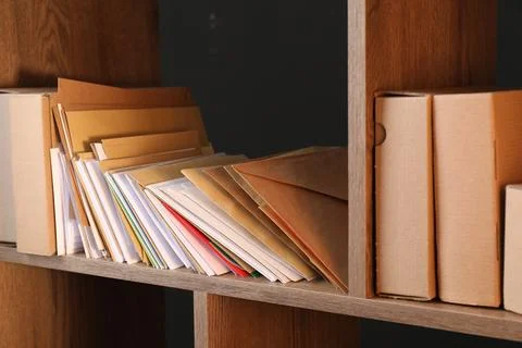 Different paper envelopes and parcels on wooden shelves in post office, close 스톡 사진