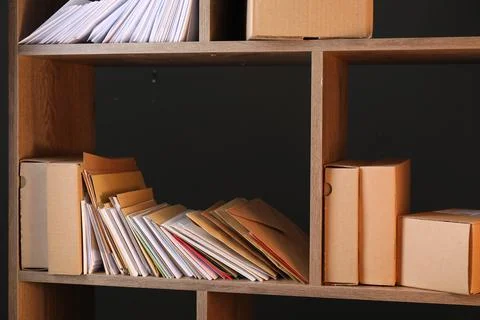 Different paper envelopes and parcels on wooden shelves in post office Stock Photos
