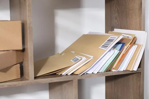 Different paper envelopes and parcels on wooden shelves in post office 스톡 사진