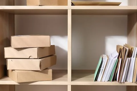 Different paper envelopes and parcels on wooden shelves in post office 스톡 사진