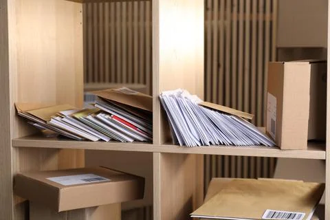 Different paper envelopes and parcels on wooden shelves in post office Stock Photos