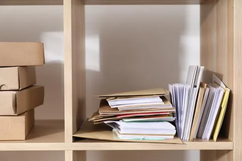 Different paper envelopes and parcels on wooden shelves in post office Stock Photos