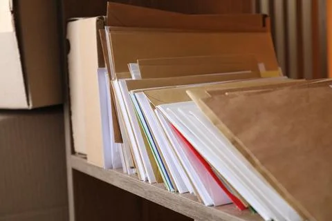 Different paper envelopes and parcels on wooden shelf in post office, closeup Stock Photos