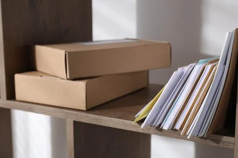 Different paper envelopes and parcels on wooden shelf in post office, closeup Stock Photos