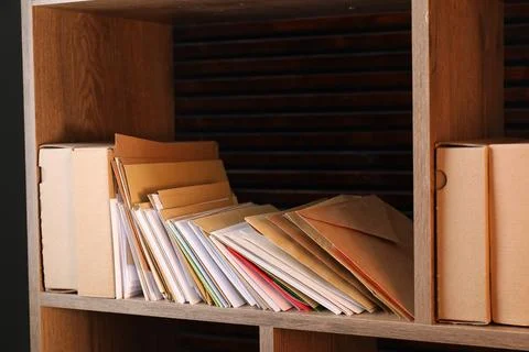 Different paper envelopes and parcels on wooden shelf in post office 스톡 사진