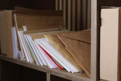 Different paper envelopes and parcels on wooden shelf in post office, closeup 스톡 사진