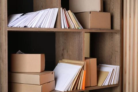Different paper envelopes and parcels on wooden shelves in post office 스톡 사진