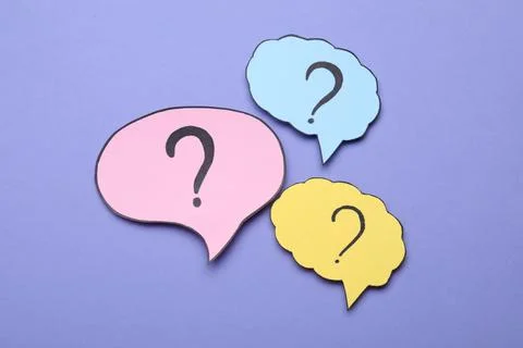 Different paper speech bubbles with question marks on violet background, fl.. Foto stock