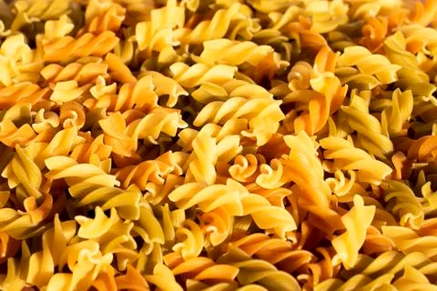 Different pasta in the form of spirals of brown, yellow and green colors Stock Photos