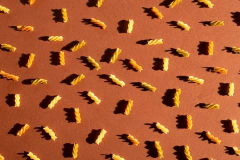 Different pasta in the form of spirals of brown, yellow and green colors Stock Photos