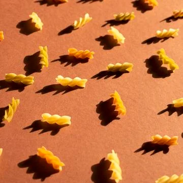 Different pasta in the form of spirals of brown, yellow and green colors Stock Photos