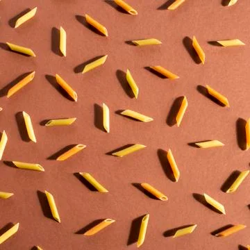Different pasta in the form of tubes of brown, yellow and green colors Stock Photos