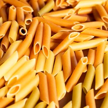 Different pasta in the form of tubes of brown, yellow and green colors Stock Photos