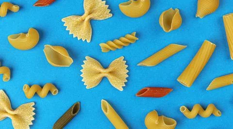 Different pasta types on blue background, top view, flat lay composition Stock Photos