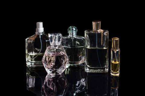 Different perfume bottles with reflections on black background with space for Stock Photos