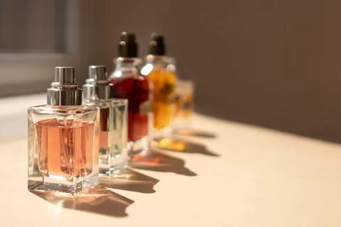 Different perfume bottles standing in row on a pastel beige background in the Stock Photos