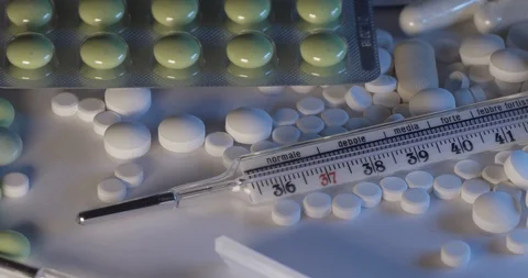 Different pharmaceutical pills and a old in glass mercury thermometer Stock Footage 125963129