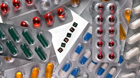 Different pills in a blister pack rotate, and in the center is the inscription Stock Footage 99808802