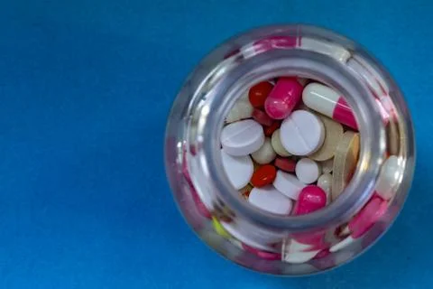 Different pills in a bottle on blue background Stock Photos