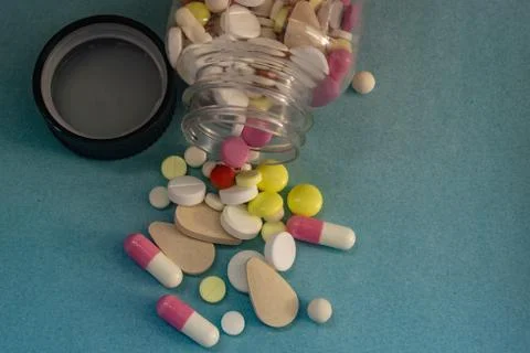 Different pills from a bottle on blue background Stock Photos