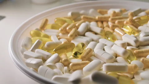 Different pills with capsules and tablets falling on white plate, white table Stock-Footage 153020689