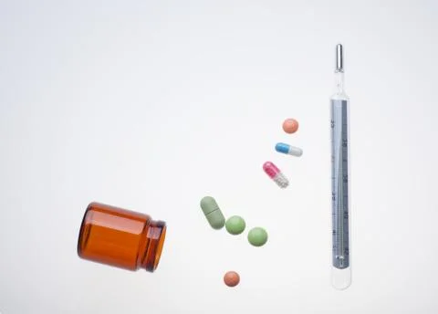 Different pills with thermometer on white background Stock Photos