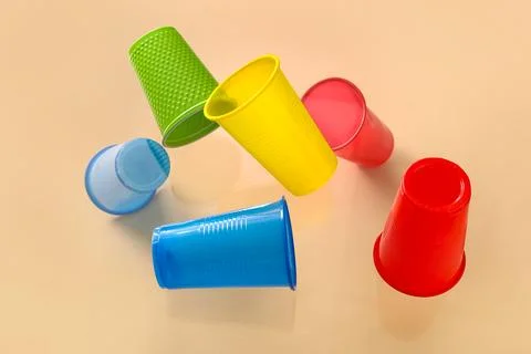 Different plastic cups levitating on beige background, closeup Stock Photos