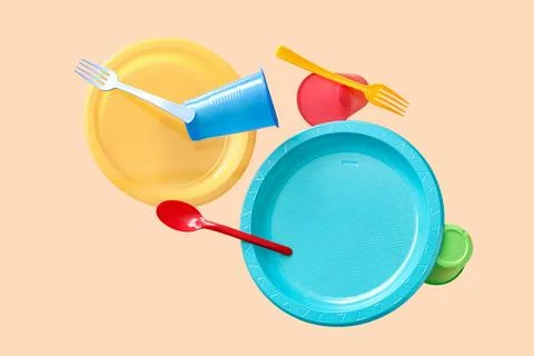 Different plastic tableware levitating on beige background Stock Photos