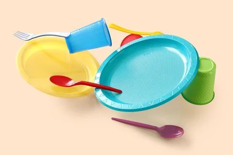 Different plastic tableware levitating on beige background, closeup Stock Photos