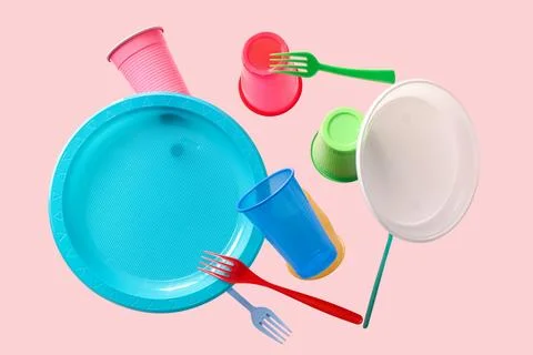 Different plastic tableware levitating on pink background Stock Photos