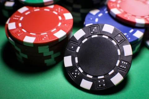 Different poker playing chips on a green table against black background. Onli Stock Photos