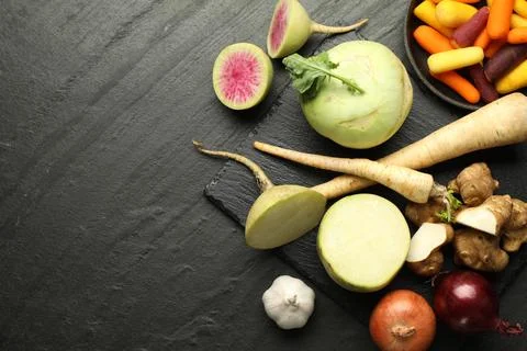 Different raw root vegetables on black table, flat lay. Space for text Stock Photos