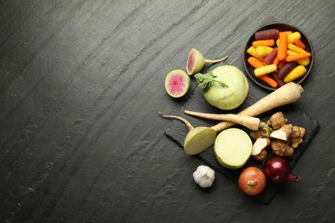 Different raw root vegetables on black table, flat lay. Space for text Stock Photos