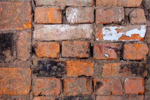 Different red bricks are laid in the wall after repair. Stock Photos