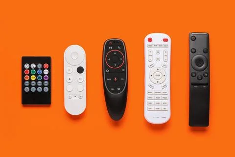 Different remote controllers on orange background 库存照片