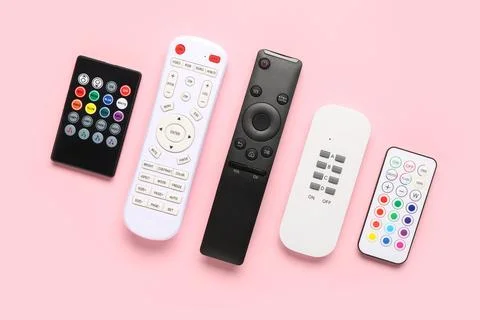 Different remote controllers on pink background 库存照片