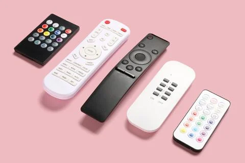 Different remote controllers on pink background 库存照片