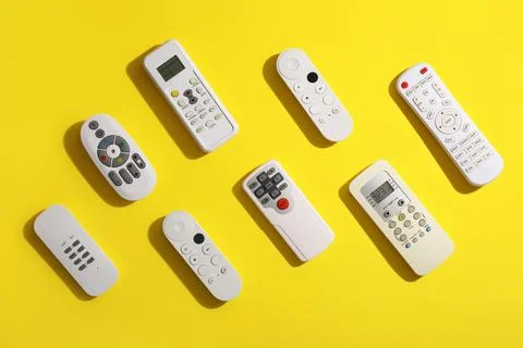 Different remote controllers on yellow background 库存照片