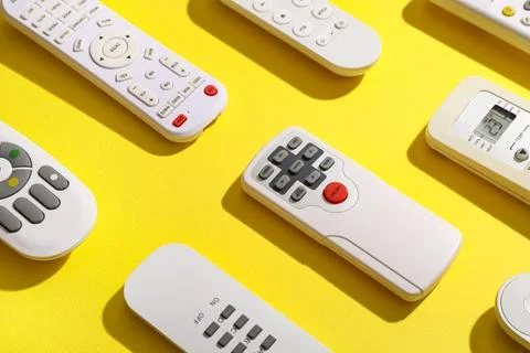 Different remote controllers on yellow background 库存照片