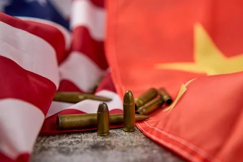 Different revolver bullets next to the Chinese and American flags. Stock Photos